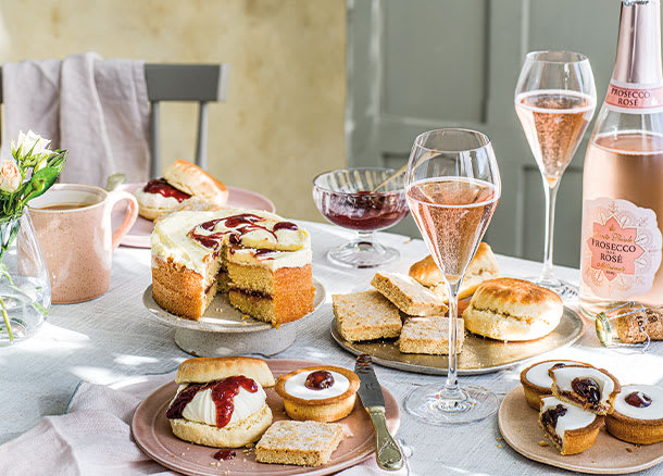 Cakes, scones and glasses of prosecco on a table