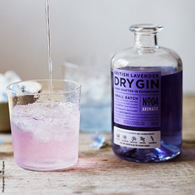 A bottle of colour-changing lavender gin poured into a glass with tonic 