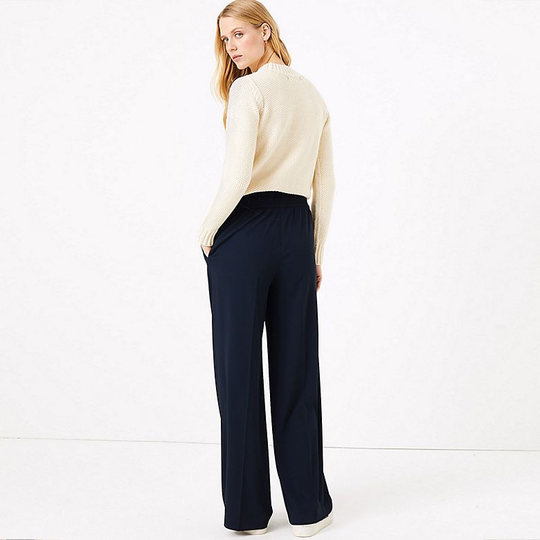 Woman wearing navy wide-leg trousers and cream jumper