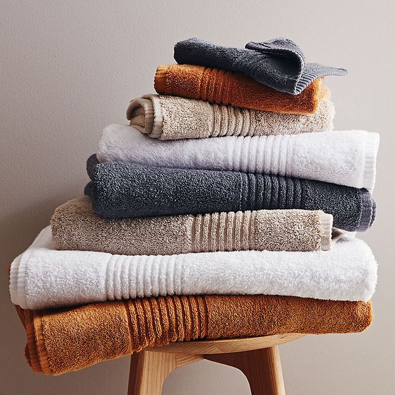 Stack of different coloured towels on a wooden stool