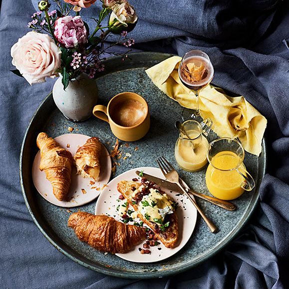 Eggs Benedict croissants on a serving tray with orange juice