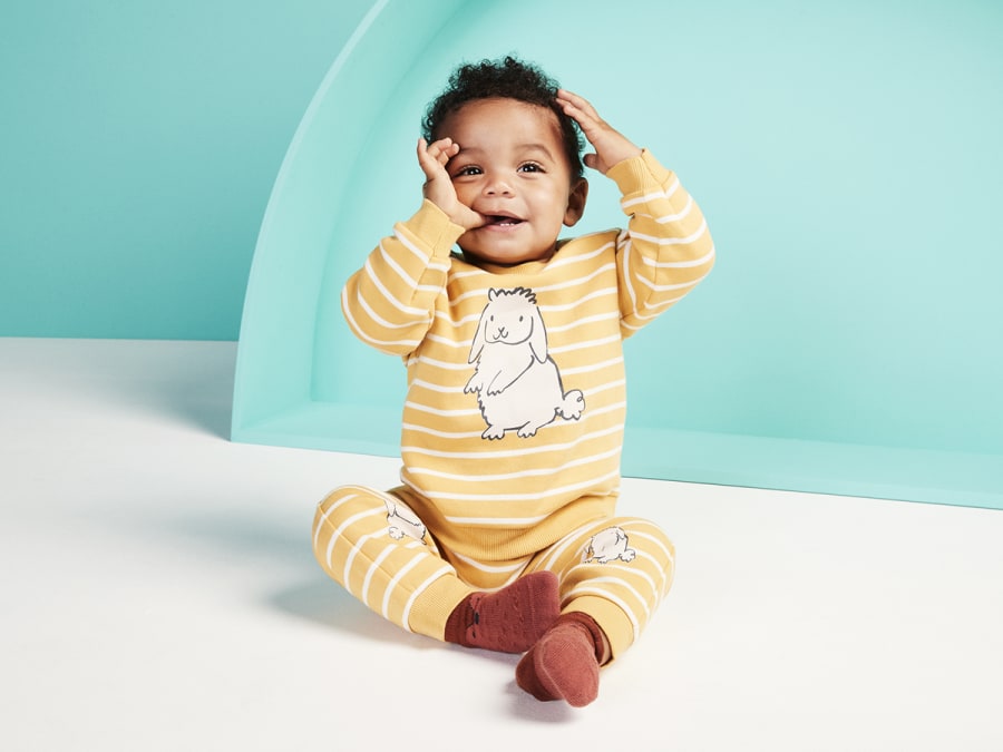 Baby wearing yellow striped babygrow