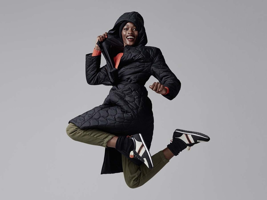 Woman wearing M&S black puffer coat with trousers and trainers