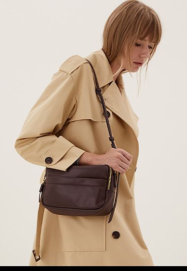 Woman wearing brown cross-body bag and beige trench coat