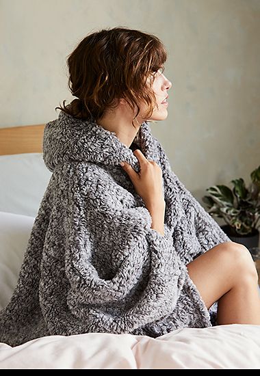 Woman wearing a grey fleece hooded blanket. Shop fleece nightwear