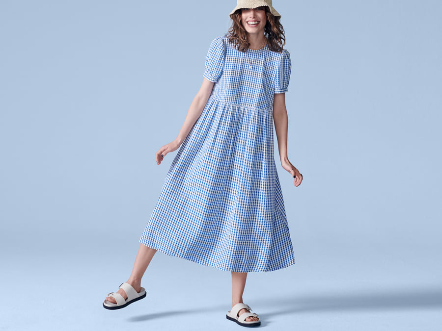 Woman wearing blue midi dress with short sleeves and ruffle hem. Shop dresses