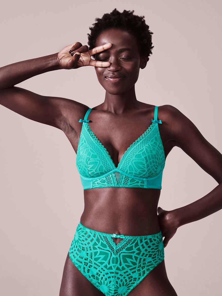 Woman wearing jade green lace bra and knicers set. Shop all bras
