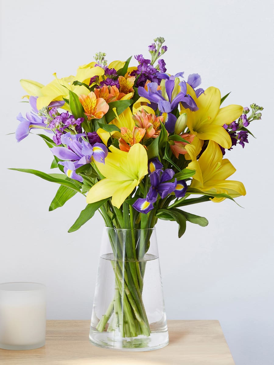 Bouquet of yellow, purple & orange flowers in a vase. Shop flowers from £25 with free delivery
