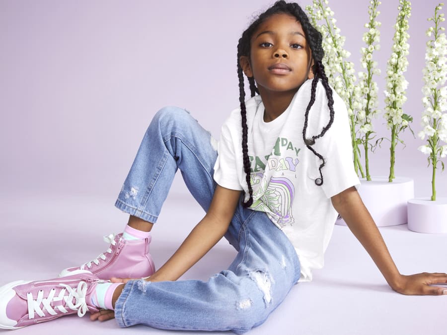 Girl wearing blue jeans, white T-shirt and pink trainers