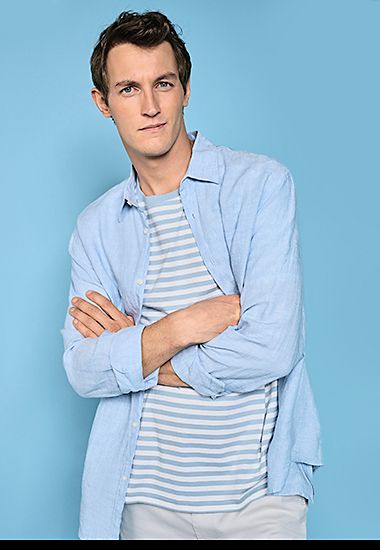 Man wearing light blue linen long-sleeved shirt, striped T-shirt and ecru chinos. Shop now. 