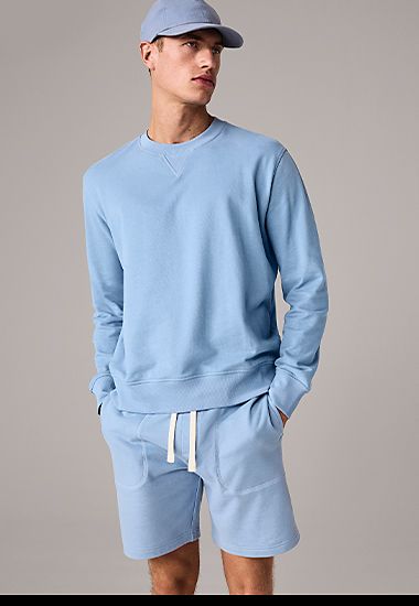 Man wearing light blue jersey sweatshirt and matching drawstring shorts. Shop now.