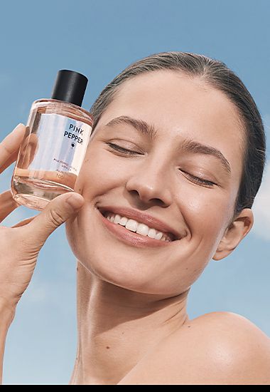 Woman holding a bottle of Pink Pepper fragrance. Shop women’s perfume.