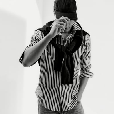 Man wearing capsule wardrobe essentials including a striped shirt. Shop men’s essential clothing 