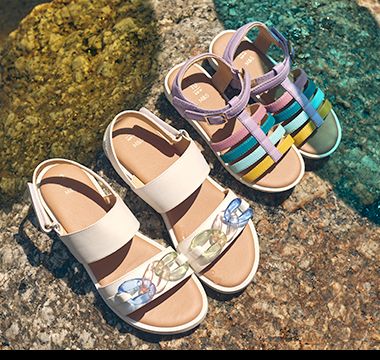 Kids’ multicoloured sandals in a rocky beach setting. Shop kids’ sandals. 