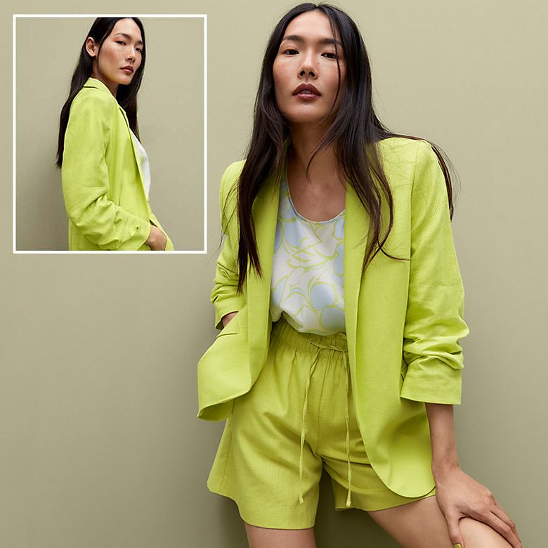 Woman wearing lime-green shorts suit. Shop women’s suits. 