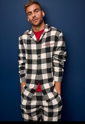 Man wearing black and white revere-collar checked pyjamas. Shop men’s nightwear 