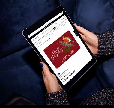 Woman’s hands holding an iPad displaying an M&S e-gift card. Shop e-gift cards
