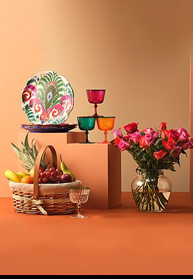 Group of gifting items including flowers, plates, glassware and a basket of fruit. Shop women’s Eid gifts.