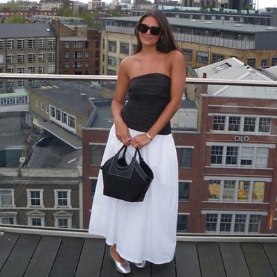 M&S Insider Zarah wearing black bandeau top, black ring-handle bag, white midi skirt and silver ballet pumps. Shop women’s summer tops 