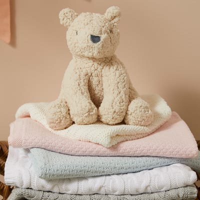 Stack of baby blankets in pink, blue, white and grey. Shop newborn essentials 