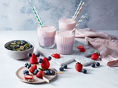Berry smoothies and berry kebabs with a bowl of blueberries 