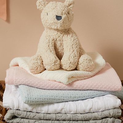 Stack of baby blankets in pink, blue, white and grey. Shop newborn essentials 