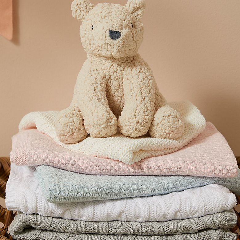 Stack of baby blankets in pink, blue, white and grey. Shop newborn essentials 