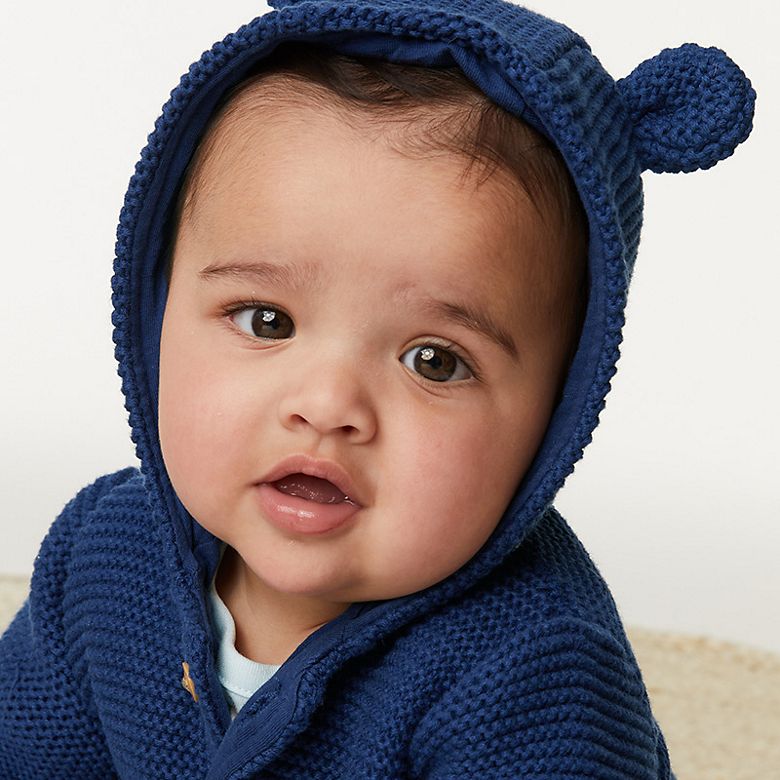 Baby wearing navy knitted cardigan with hood and ears. Shop now