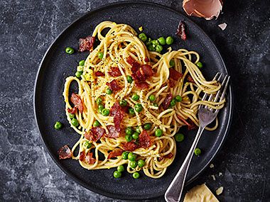 A spaghetti dish with bacon and peas