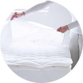 Model fitting a sheet over a mattress