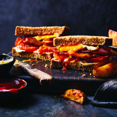 Stacked bacon, egg and charred tomato sandwiches with spicy potato wedges 