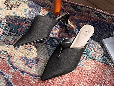 Black point-toe kitten heels on a patterned rug