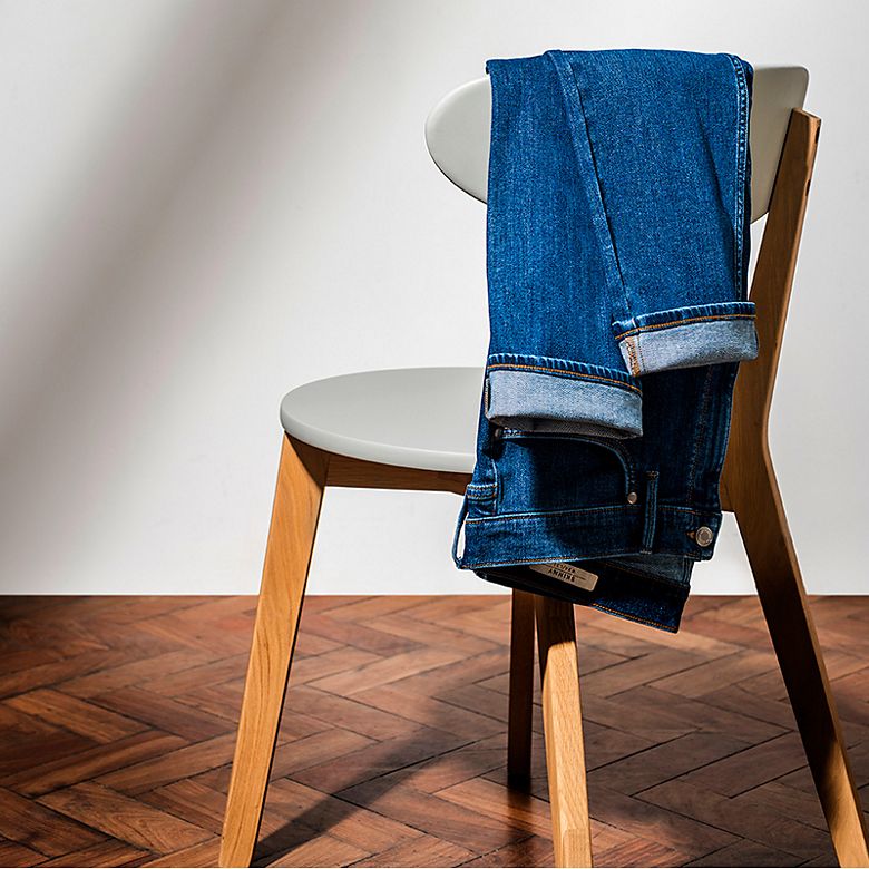 Men’s slim-fit blue denim jeans laid over a chair