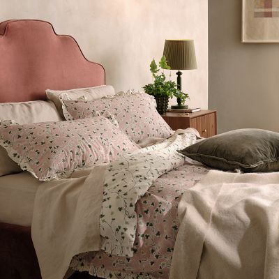 Bed made up with matching duvet set, pillows and cushions. Shop bedding