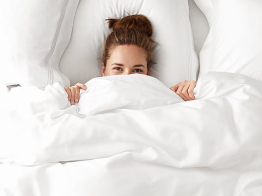 Woman in bed surrounded by white bedding