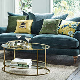 Teal velvet sofa and gold and glass coffee table in a living room