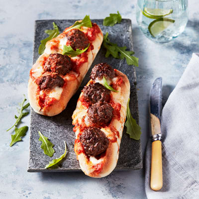 Two meatball subs with melted mozzarella and rocket