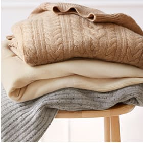 Folded jumpers on a wooden stool