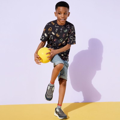 Boy wearing T-shirt, shorts and trainers