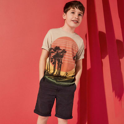 Boy wearing T-shirt, shorts and trainers