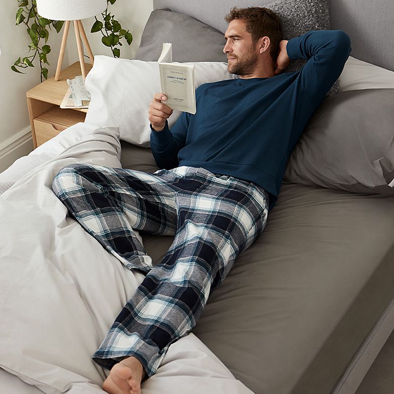 Man wearing navy pyjama top and blue and white checked pyjama bottoms