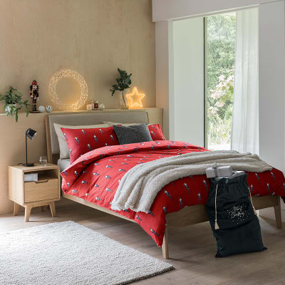 Bedroom with pale wooden furniture and red nutcracker-print bedding