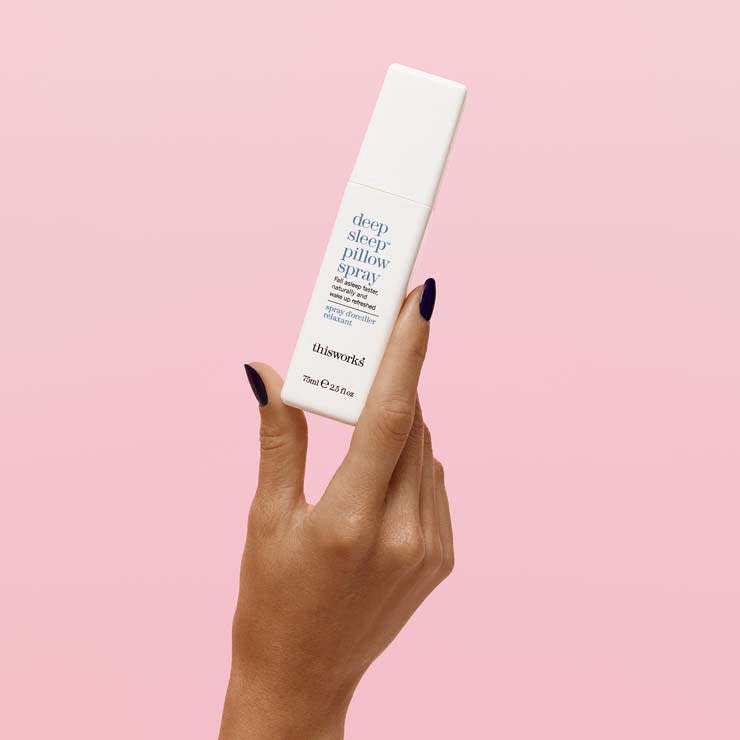 Woman holding This Works Deep Sleep pillow spray