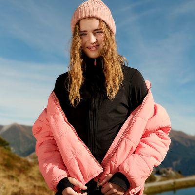 Girl wearing pink padded jacket and beanie hat. Shop kids’ outerwear