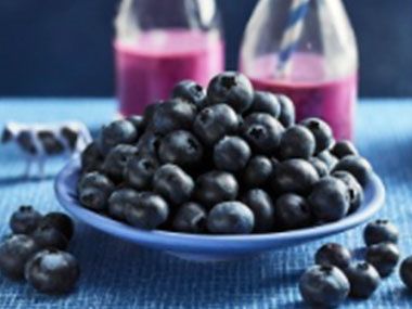 A bowl of blueberries and two berry smoothies