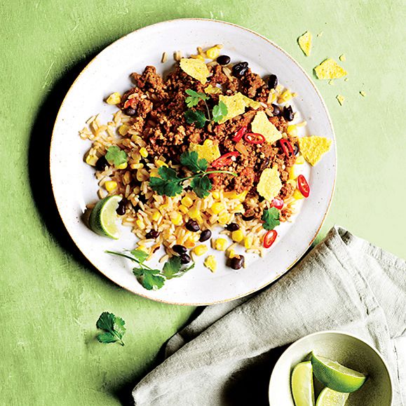 Mexican beef chilli with rice, lime wedges and coriander 
