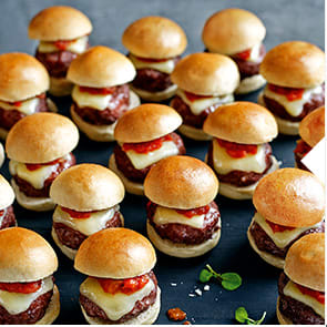 Mini cheese burgers on a wooden board
