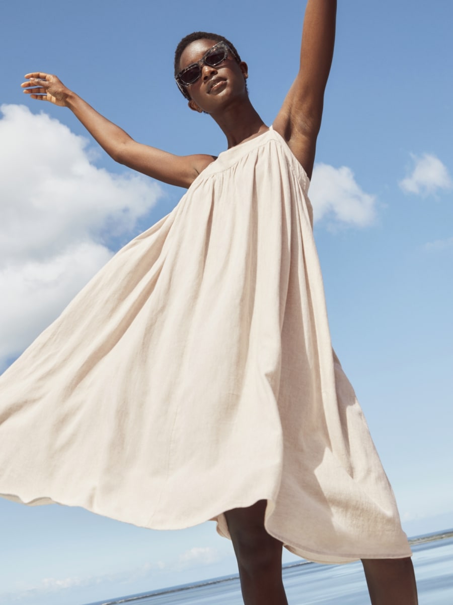 Woman wearing white beach dress. Shop dresses