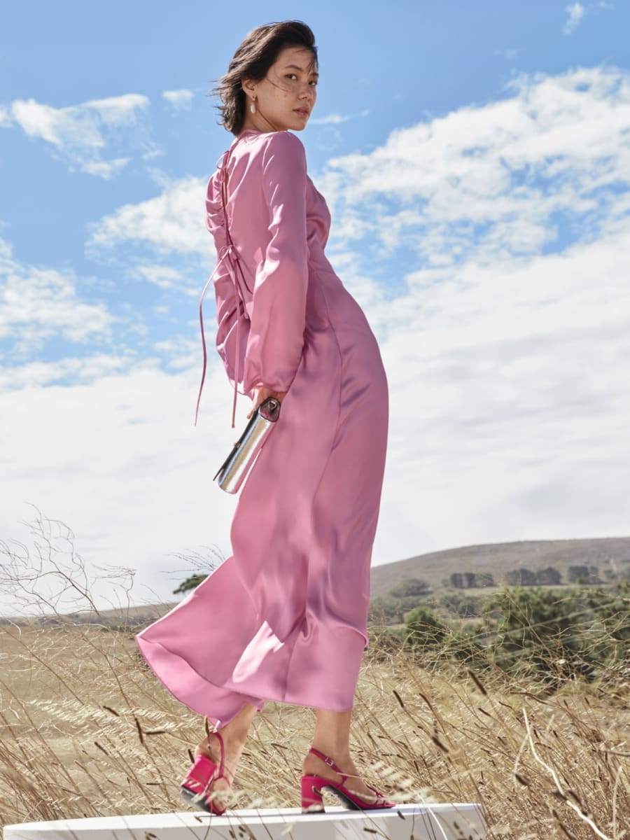 Woman wearing pink dress and pink high-heeled sandals. Shop high heels