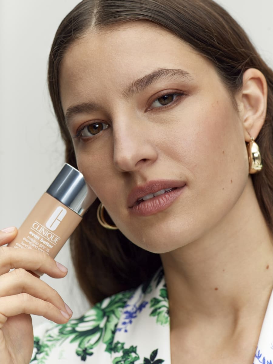 Woman holding Clinique foundation bottle. Shop Clinique